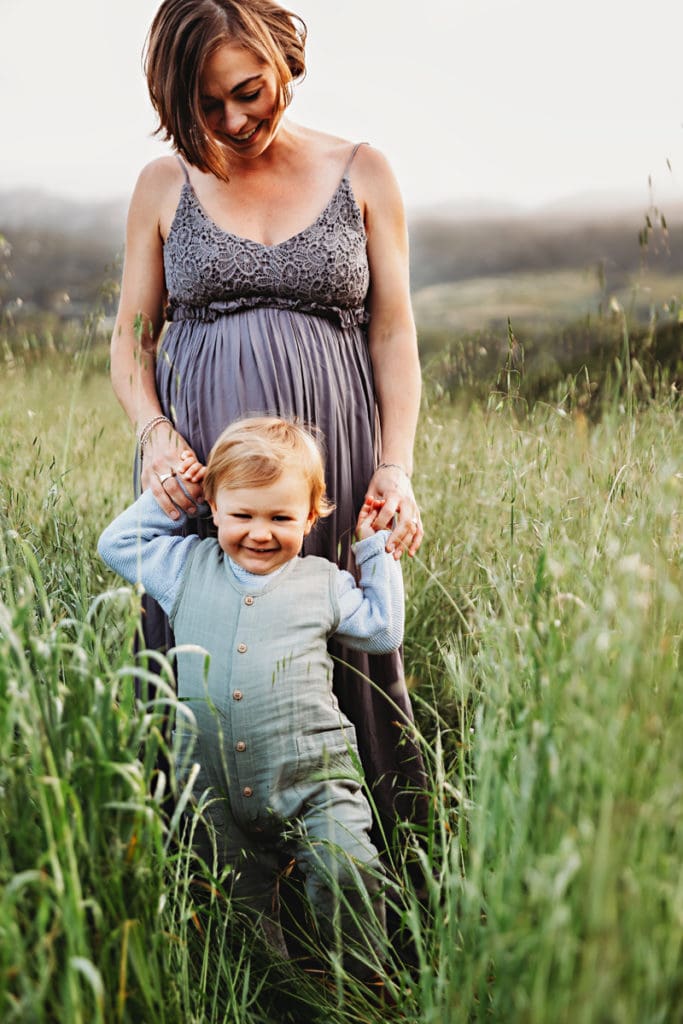 Family Photographer, a mother and her toddler walk through a meadow