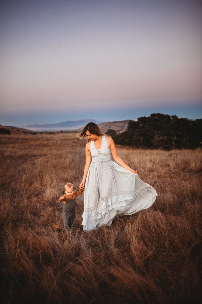 Family Photographer, Mom and child walk through a dry field at dusk